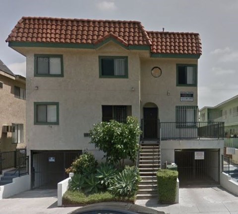 A two-story building with a red tile roof and a balcony on the second floor.