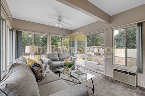 A living room with a grey couch and a glass table.