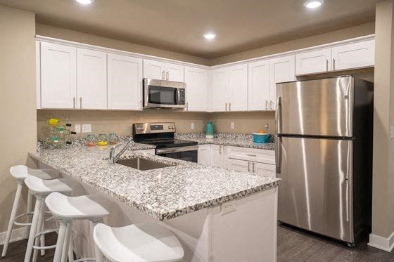 a kitchen with a granite counter top and a stainless steel refrigerator