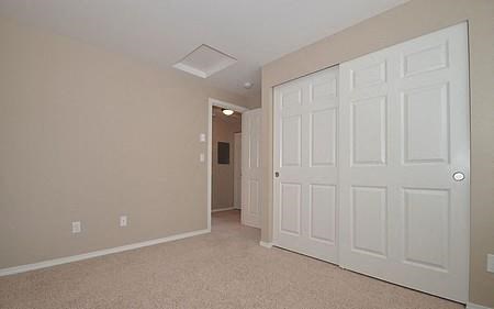a large empty bedroom with two closets and a door