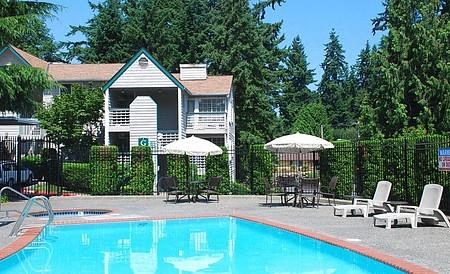 a swimming pool with chairs and umbrellas in front of a house
