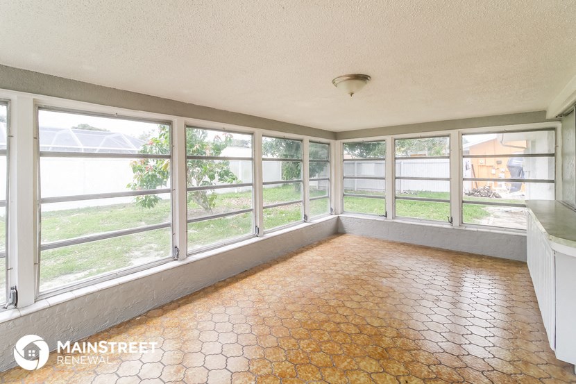 an empty living room with large windows and a tile floor