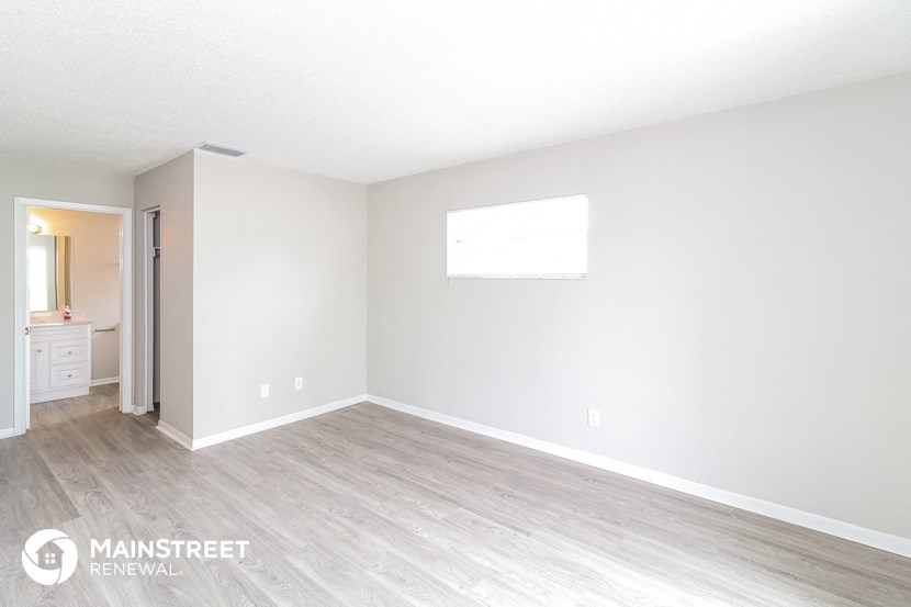 the spacious living room with white walls and wood flooring