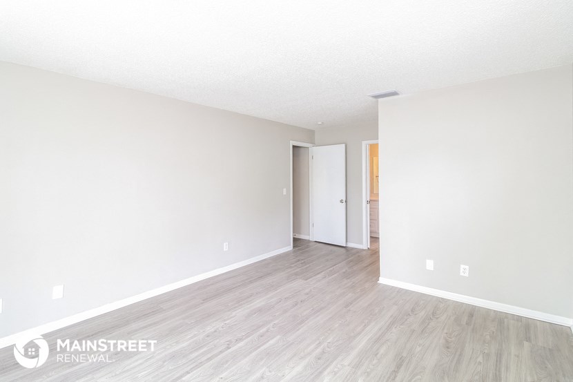 the living room of an apartment with wood floors and white walls