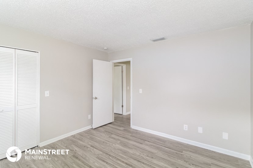 the spacious living room with white walls and wood flooring