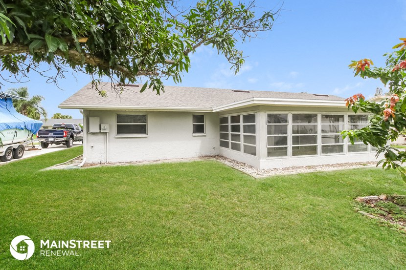 a white house with a lawn and a tree
