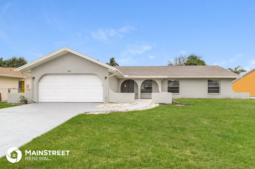 a white house with a driveway and a lawn