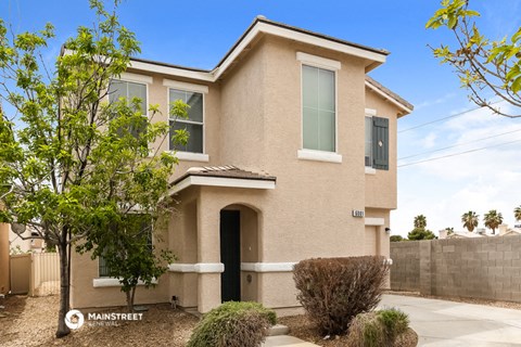 a tan house with a black door and a tree