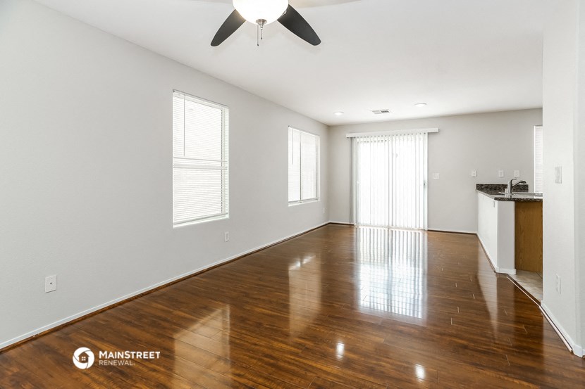 an empty living room with wood floors and a ceiling fan