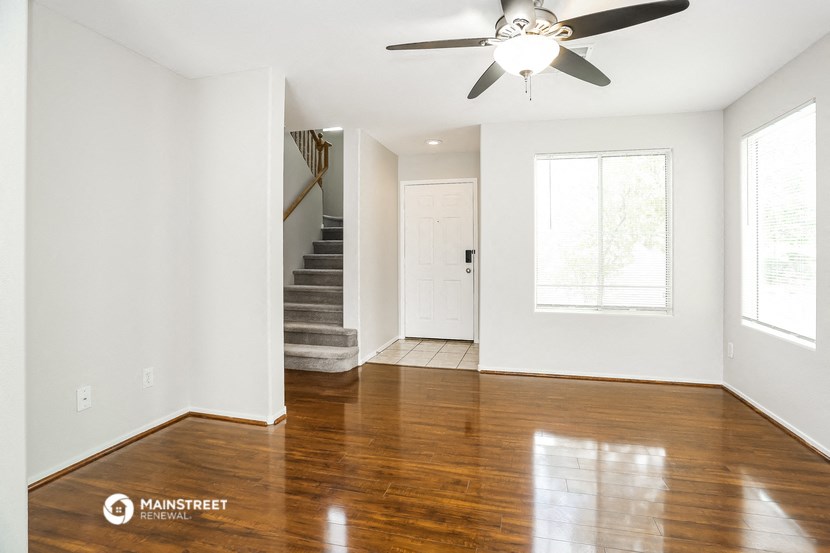 an empty living room with wood floors and a ceiling fan