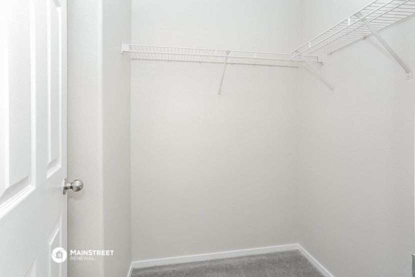 a walk in closet in a white room with a white door