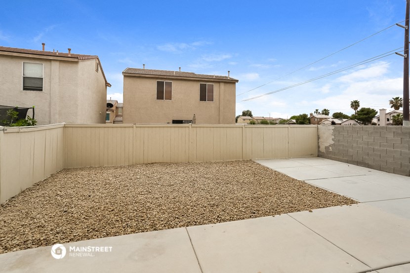 a back yard with a fence and a house in the background