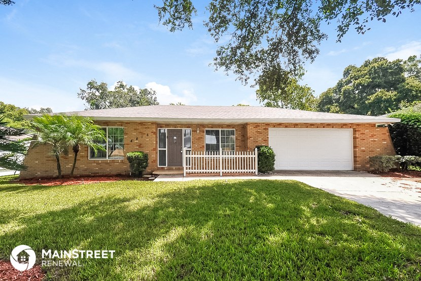 a small brick house with a lawn and a white fence