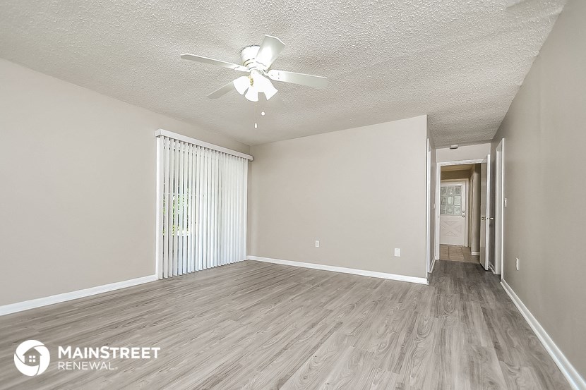 the spacious living room with ceiling fan and wood flooring