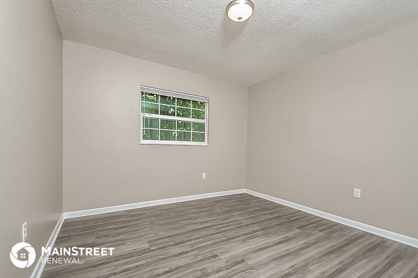 the living room of a rental house with wood flooring and a window