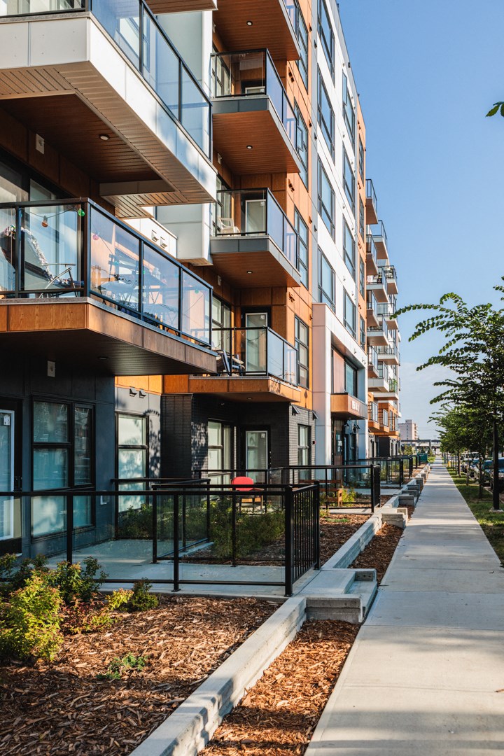 A modern apartment building with balconies and a sidewalk.