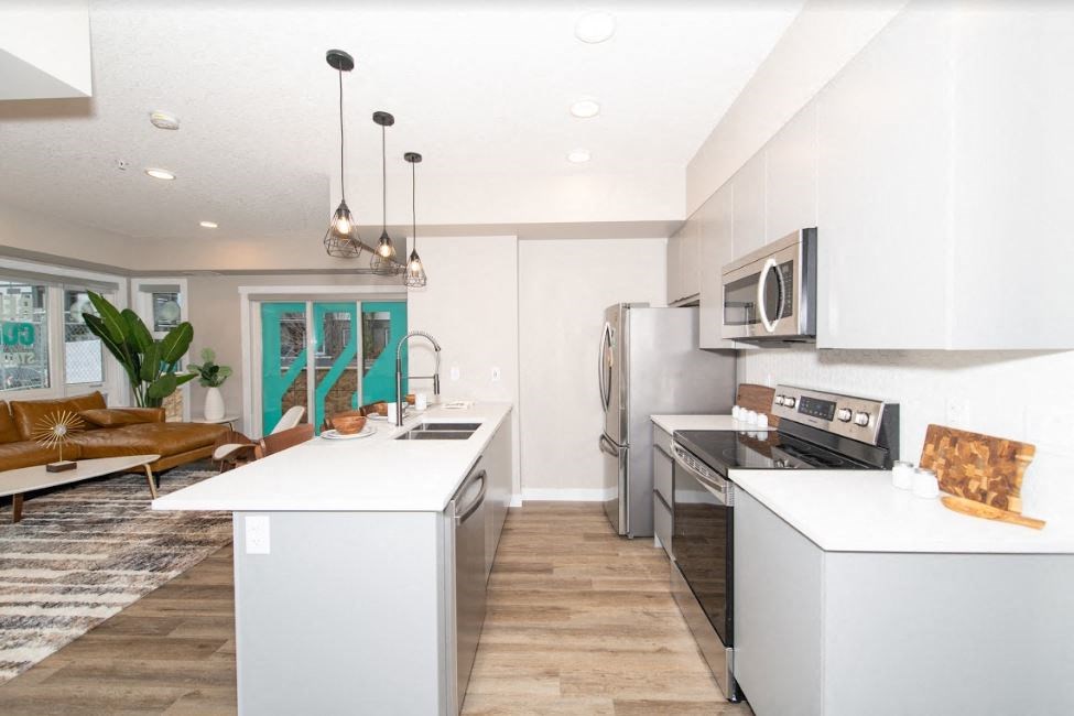 a white kitchen with stainless steel appliances and white counter tops