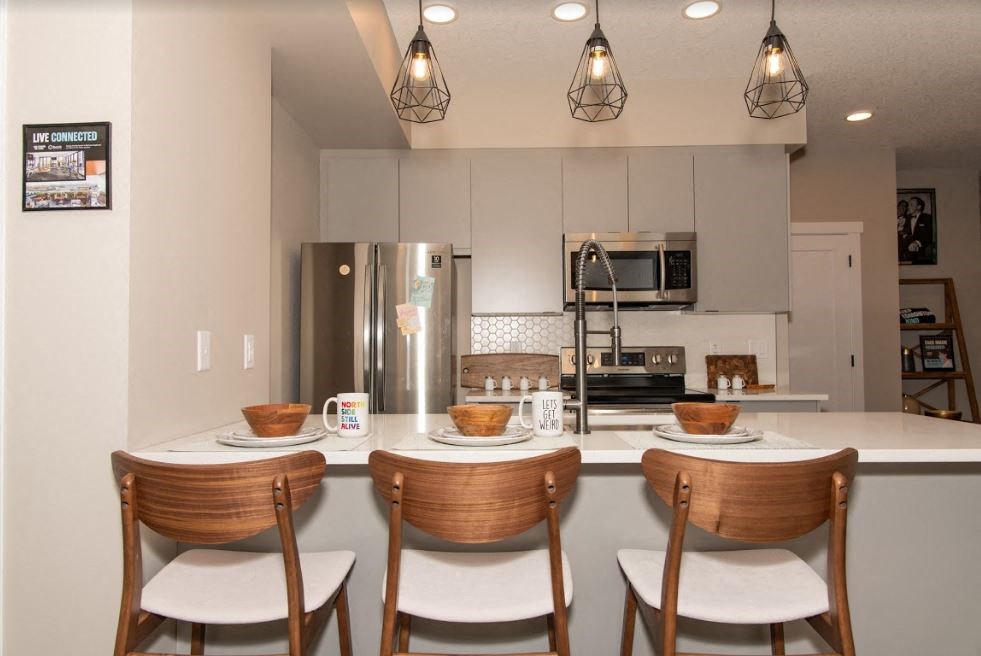 a kitchen with a counter with three chairs