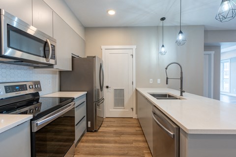 A modern kitchen with stainless steel appliances and wooden flooring.