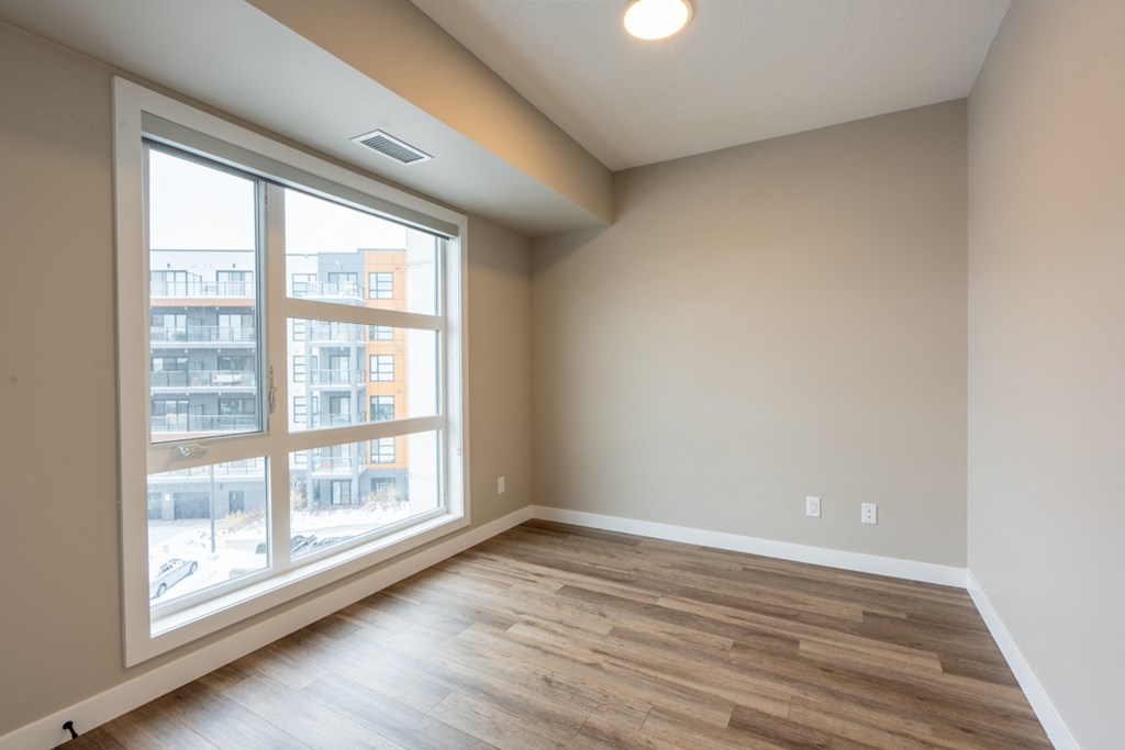 A room with a large window and wooden flooring.
