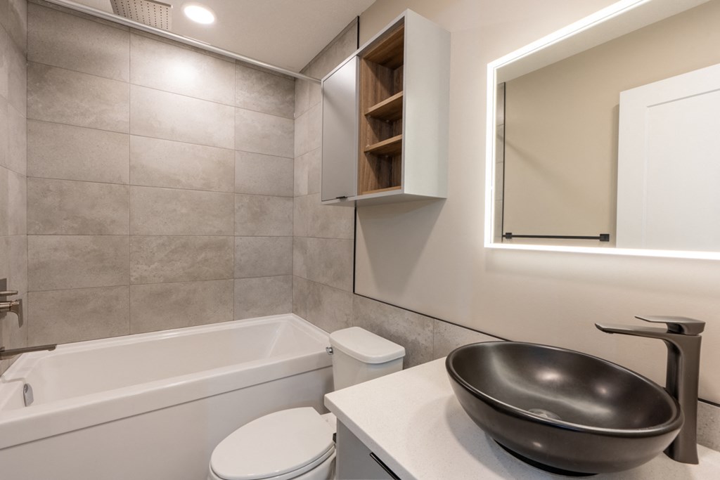 A modern bathroom with a white toilet, a white sink, and a white bathtub.