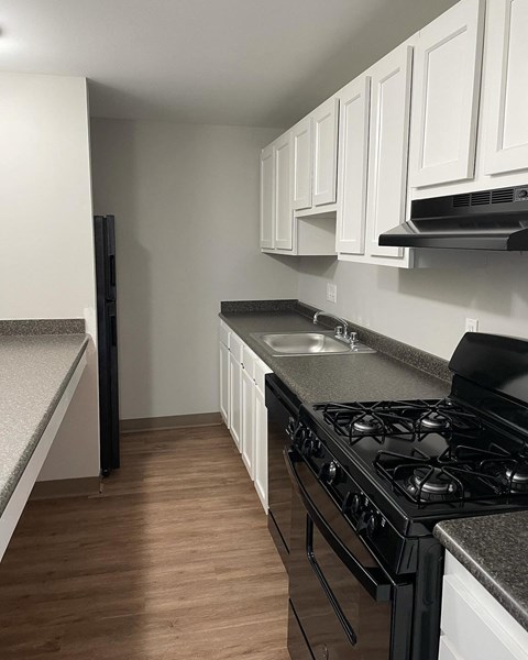 a kitchen with white cabinets and a stove and a sink