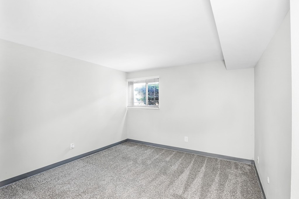 A room with a window and carpeted floor.