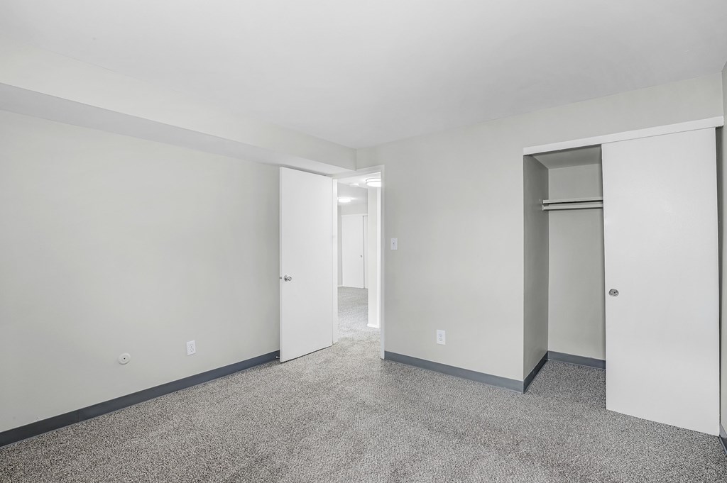 A spacious room with a carpeted floor and white walls.