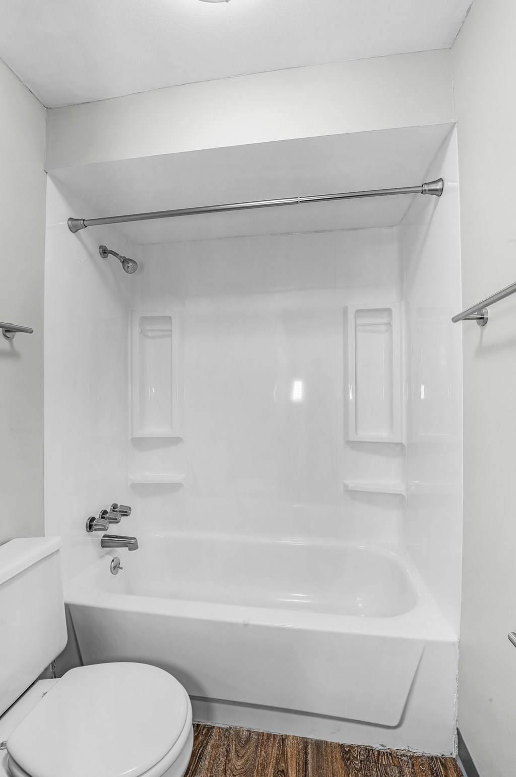 A white bathroom with a toilet, tub, and towel rack.