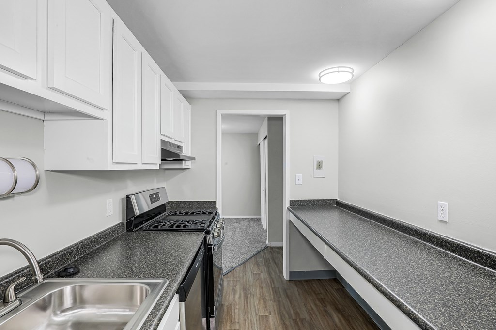 A kitchen with white cabinets and a black stove top oven.