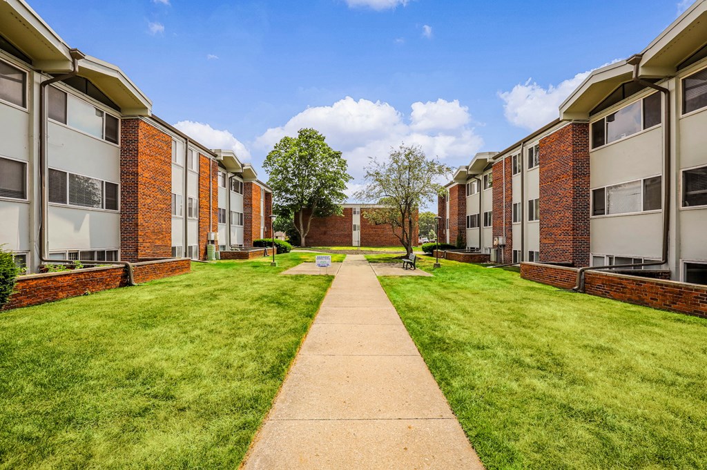 A long concrete walkway leads between two rows of apartment buildings.