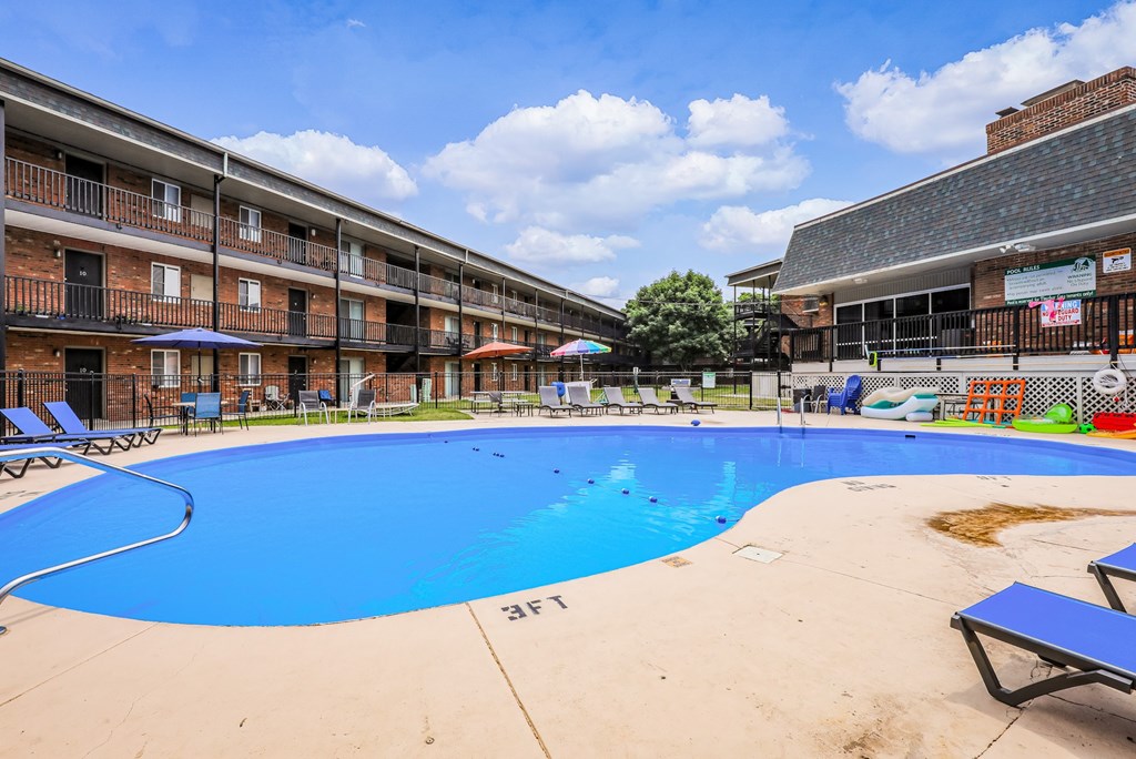 A large blue swimming pool in front of a building with a poolside bar.