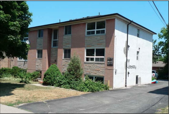 a brick building with a white wall and some bushes