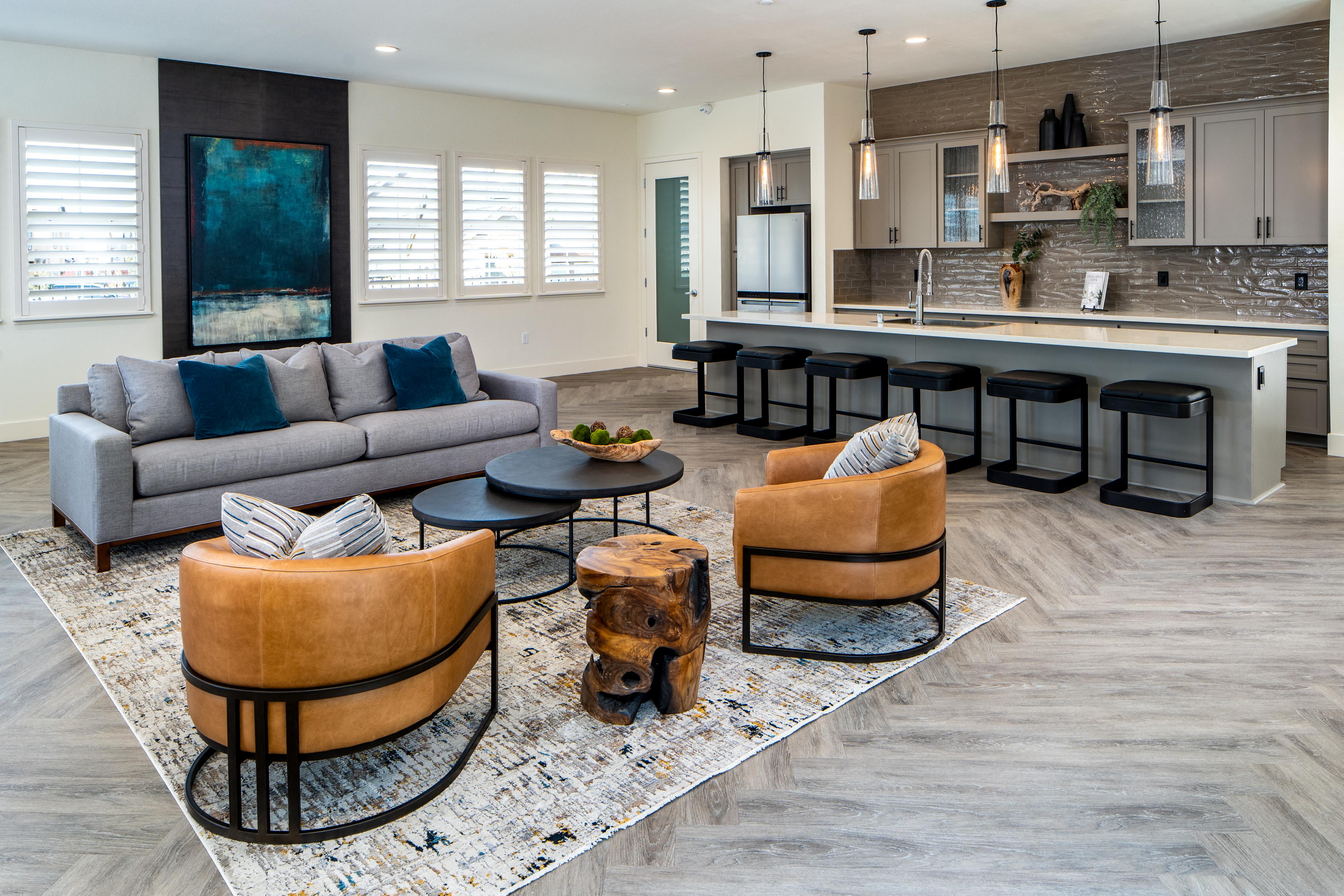 a living room with a couch and chairs in front of a kitchen