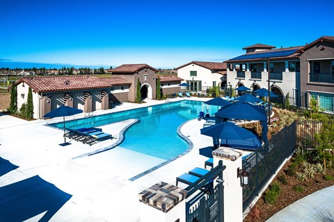 a large swimming pool with umbrellas in front of a building
