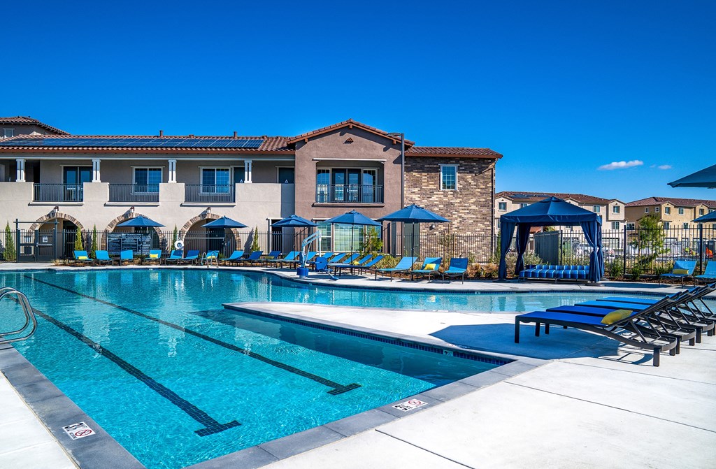 a swimming pool with lounge chairs and a building in the background