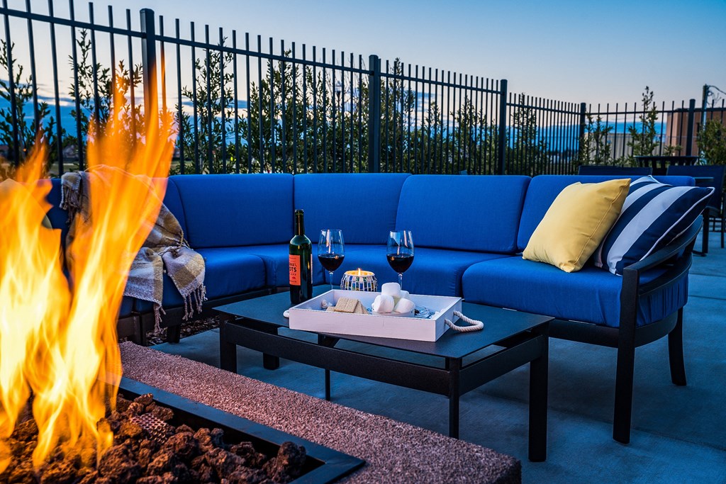 a lounge area with a fire pit and blue couches