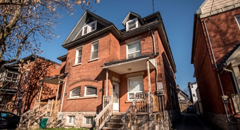 A red brick house with a black car parked in front.