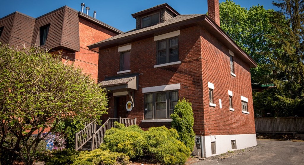 the front of a brick house with stairs and trees