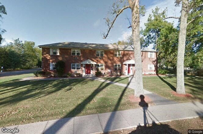 a red brick house with a yard and trees