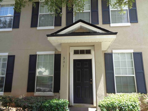 A house with a black front door and windows with black shutters.
