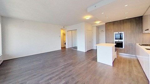 the living room and kitchen of an apartment with wood floors and white walls