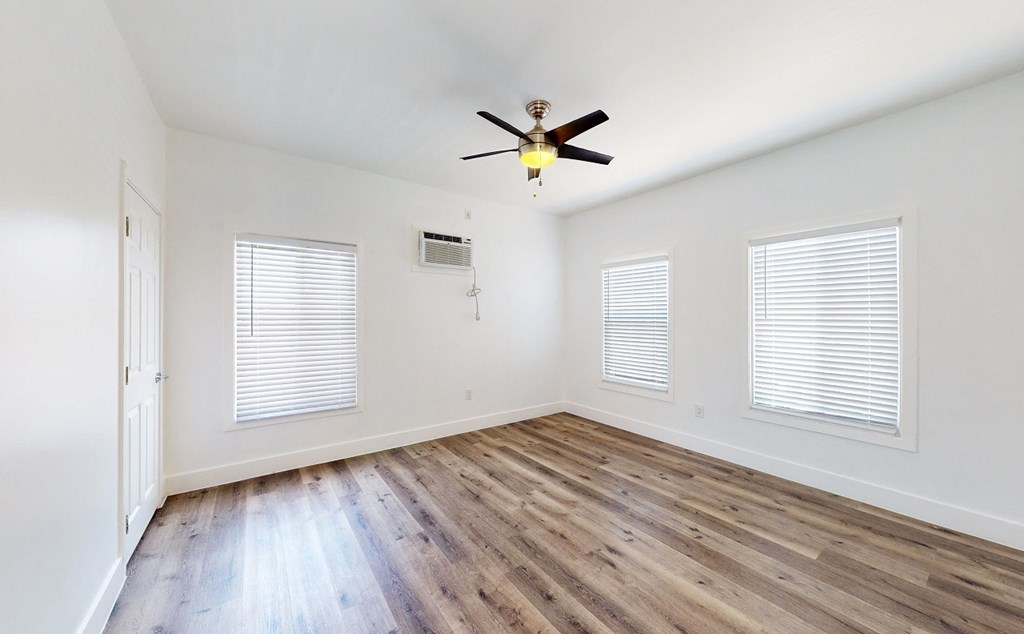 an empty living room with wood floors and a ceiling fan
