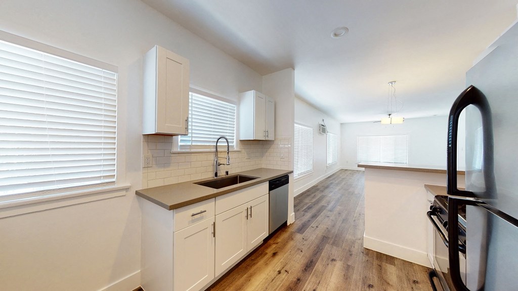 an empty kitchen with white cabinets and a large window