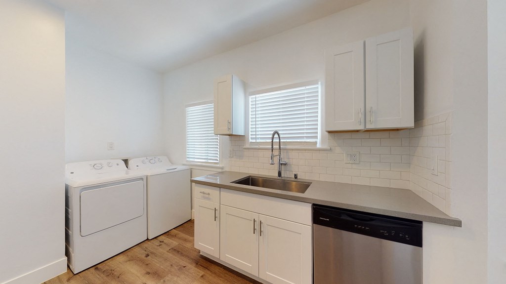 a kitchen with white cabinets and a sink and a washer and dryer