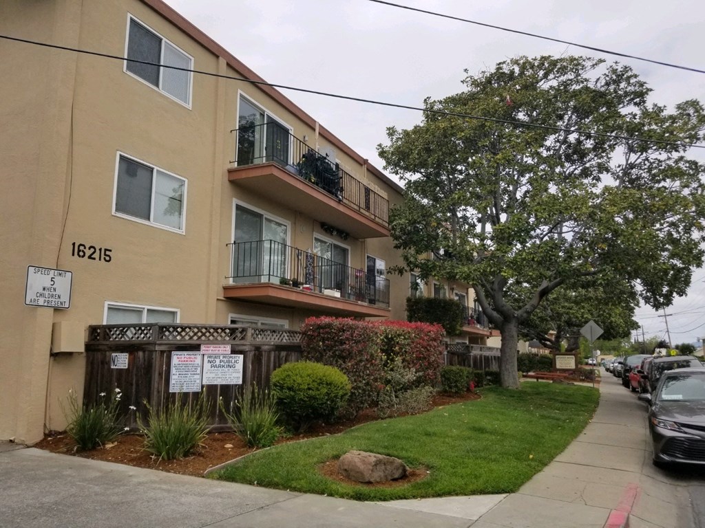 an apartment building on a city street with a sidewalk and a fence