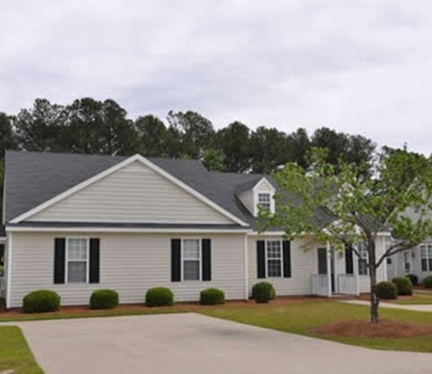 A white house with black shutters and a grey roof.