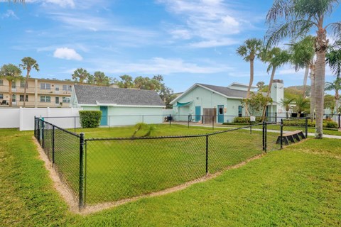 A house with a green roof is surrounded by a black fence.