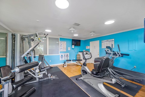 A gym with a variety of equipment including treadmills, weights, and exercise machines.