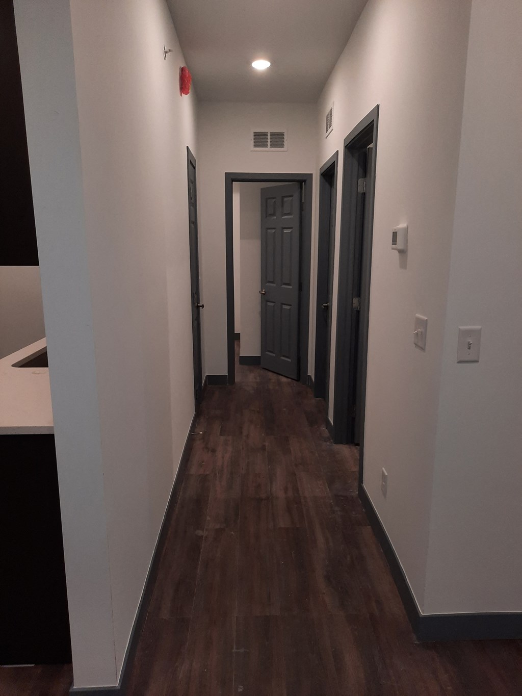 a hallway with white walls and wooden floors and a blue door